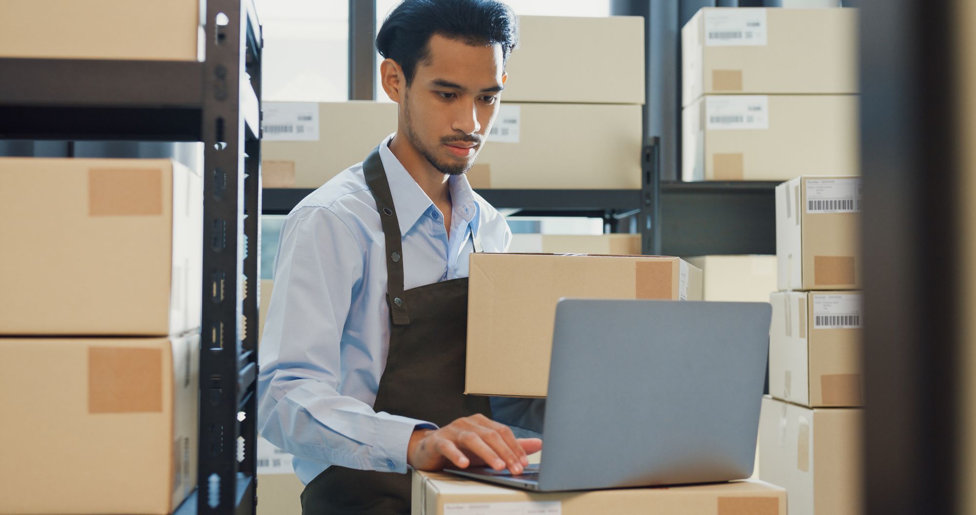 A man checking inventory data on a laptop in a warehouse.