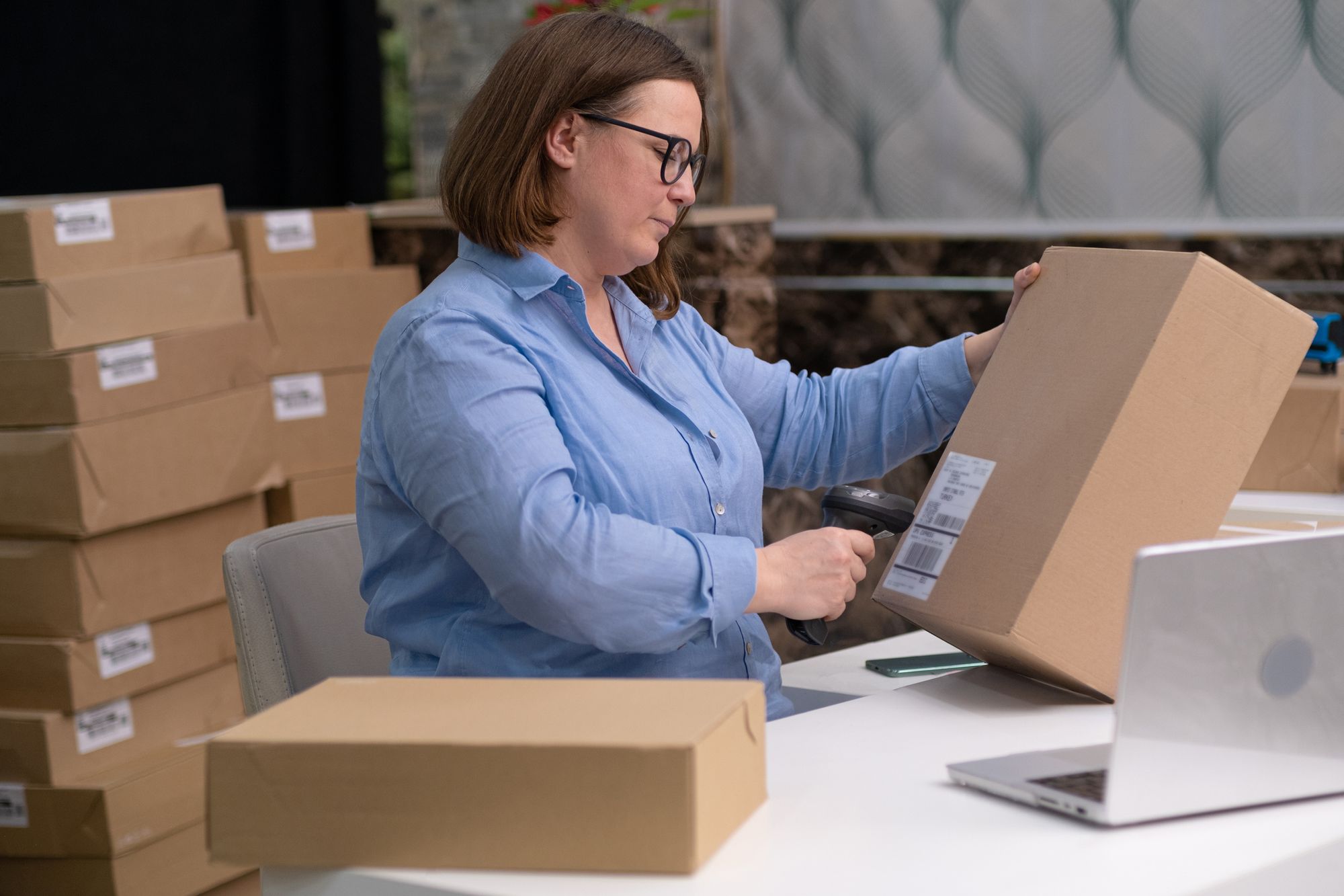 A woman is scanning a barcode attached to a box.