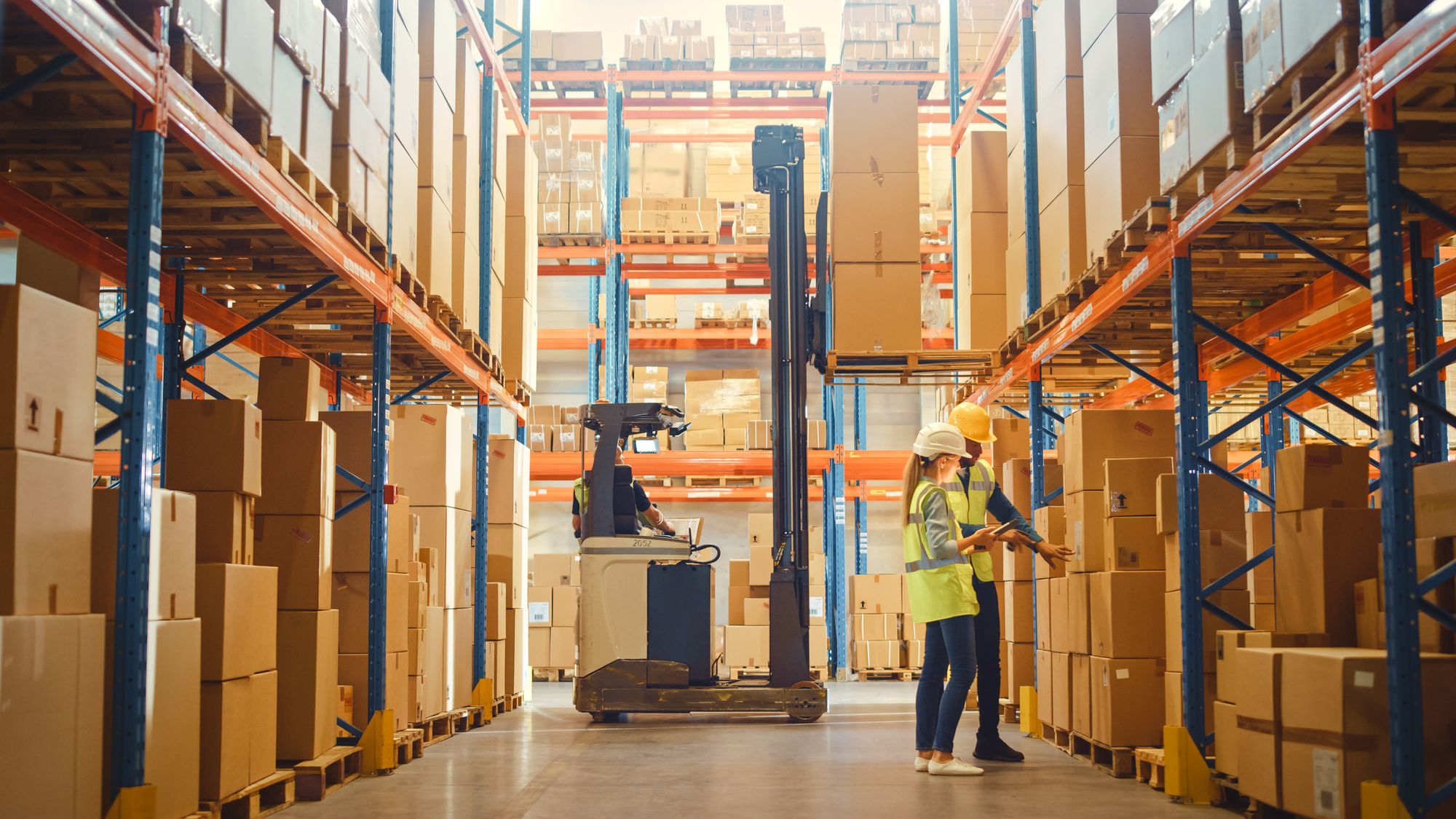 Workers in the warehouse moving products while checking the order list.