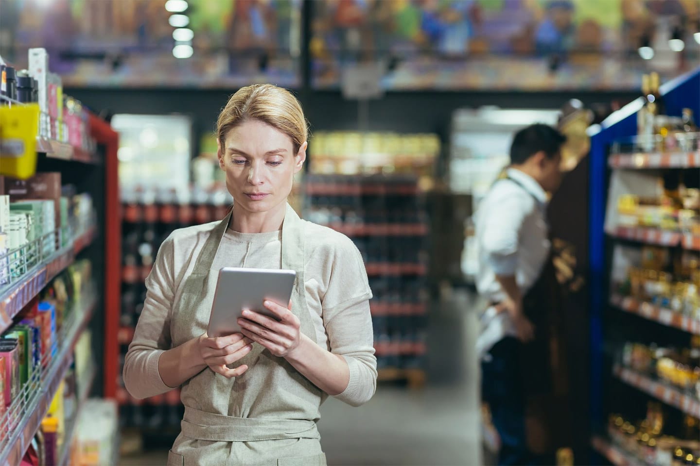 슈퍼마켓의 여성 관리자가 태블릿을 사용하여 재고 수량을 확인하고 있는 모습.