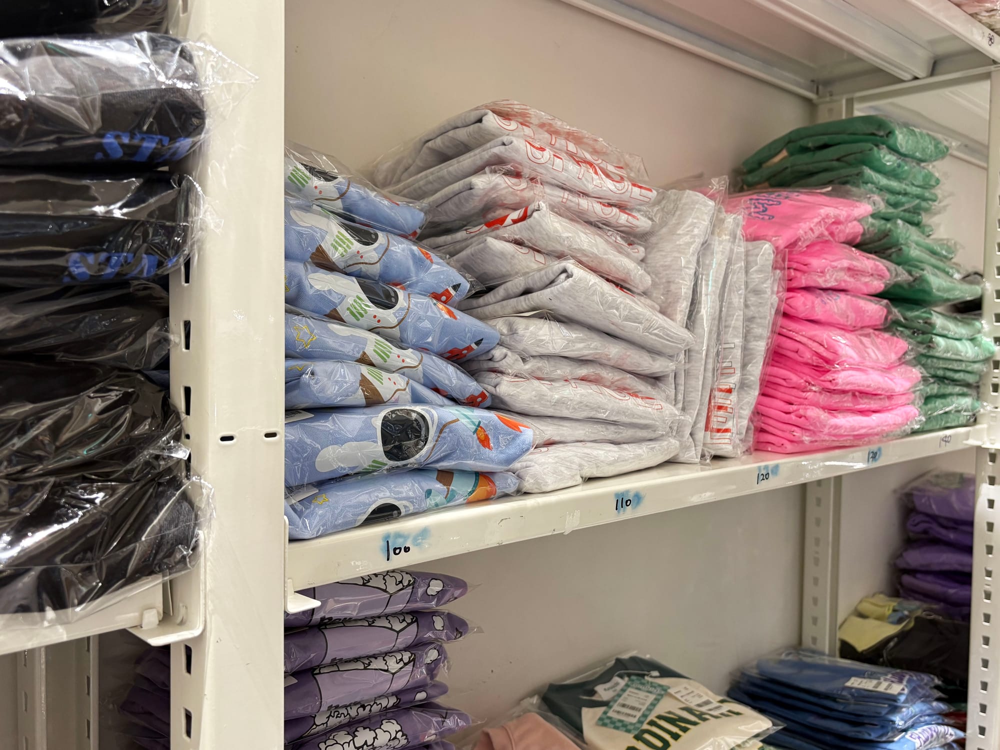 철제 선반에 포장된 의류들이 쌓여있다.